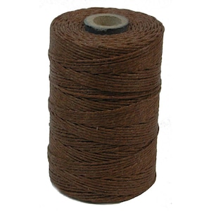 May include: A spool of brown waxed linen thread.