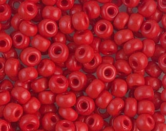 May include: A close-up image of a pile of small, red, round seed beads. The beads are made of plastic and have a smooth, glossy finish.