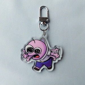 Puede incluir: Un llavero de acr&iacute;lico transparente con un personaje de dibujos animados rosa con ojos grandes y una expresi&oacute;n de sorpresa. El personaje lleva una camisa blanca y pantalones azules. El llavero tiene un anillo de metal plateado.