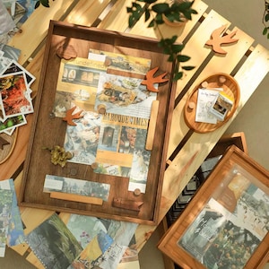 May include: A rectangular wooden bulletin board with a dark brown finish, featuring various paper clippings, small wooden bird-shaped magnets, and rectangular wooden strips. A smaller oval wooden tray and a second wooden frame are also visible.