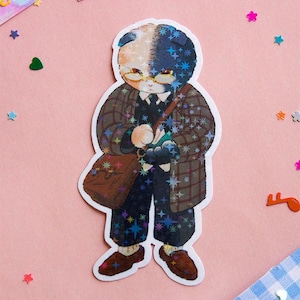 May include: A sticker of a cat wearing a plaid coat, glasses, and a satchel. The cat has a black and white face and is surrounded by a glittery background.