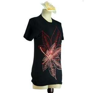 May include: Black t-shirt with a red and pink leaf design printed on the front.