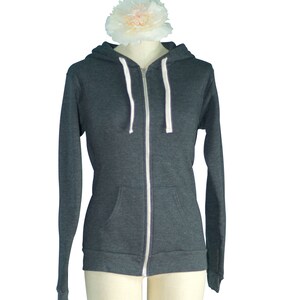 May include: A dark gray zip-up hoodie with a white zipper and white drawstrings.