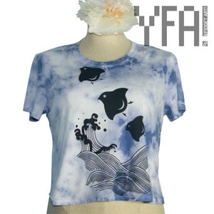 May include: A blue tie-dye t-shirt with a black and white graphic of three stingrays and waves. The text "YFA" is in the upper right corner of the image.