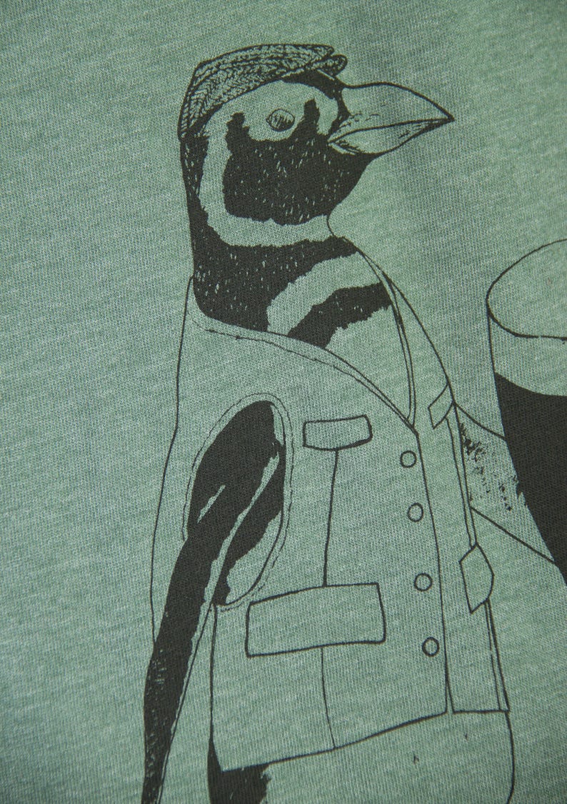 May include: A green t-shirt with a black and white illustration of a penguin wearing a vest and holding a glass of beer.