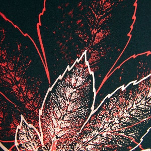 May include: A close-up of a black fabric with a red and white leaf pattern. The leaves are printed in a distressed style, giving the fabric a vintage look.