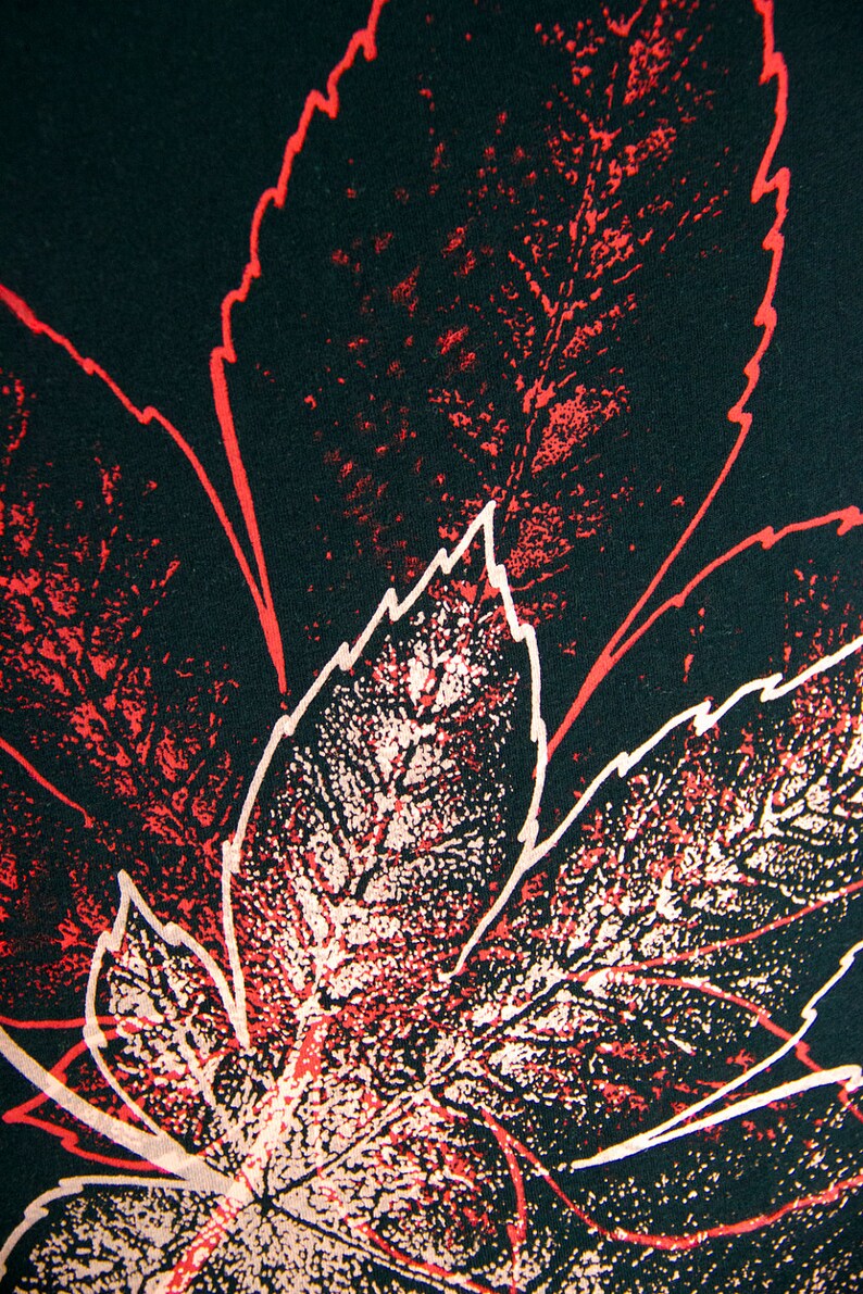 May include: A close-up of a black fabric with a red and white leaf pattern. The leaves are printed in a distressed style, giving the fabric a vintage look.