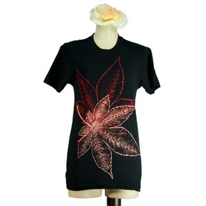 May include: Black t-shirt featuring a red and orange leaf design.