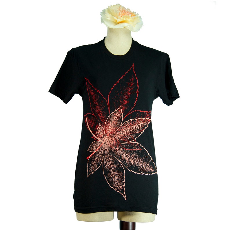 May include: Black t-shirt featuring a red and orange leaf design.