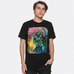 May include: Black t-shirt with a vibrant graphic of a hooded character in green and blue armour. The illustration is in a comic book style, set against a pink and yellow backdrop. The figure is kneeling with an arm raised.