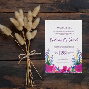 May include: A wedding invitation with a watercolor floral design in shades of pink, purple, blue, and yellow. The invitation reads "Nuestra Boda" and includes the names Antonio & Isabel, the date Saturday, November 26, 2024, and the time 09 PM. The invitation also includes the address Calle 123, Cualquier Ciudad.
