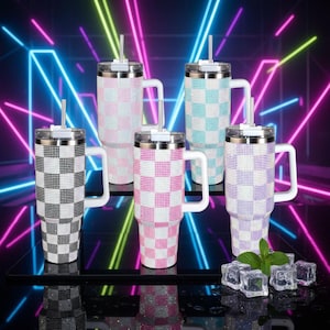 May include: Five tall stainless steel tumblers with handles and straws, each featuring a checkered pattern made of small rhinestones. The tumblers come in black, light pink, light blue, and purple, arranged in a group with ice cubes nearby.