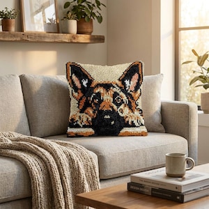 May include: A square throw pillow featuring a textured punch needle design of a German Shepherd dog face. The dog is depicted in shades of black, tan, and cream, with its paws resting at the bottom edge of the pillow against a light cream background.