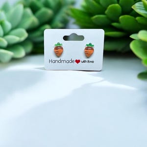 以下が含まれることがあります： 白いカードに「Handmade with love」と書かれた、ニンジン型のイヤリングのペアです。