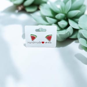 以下が含まれることがあります： 白いカードに「Handmade with love」と書かれた、スイカの輪切りのイヤリングのペアです。