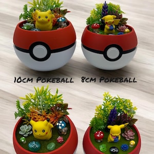 Op de afbeelding: Twee rood-witte Pok&eacute;ball-plantenbakken, 10 cm en 8 cm in diameter, elk gevuld met groen, miniatuurpaddenstoelen en een gele Pikachu-figuur. De plantenbakken zijn ontworpen in de stijl van de Pok&eacute;ball uit de Pok&eacute;mon-serie.