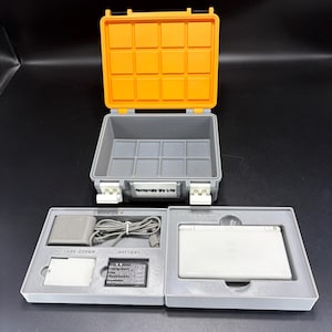 May include: An open grey and orange Nintendo DS Lite carrying case with a white Nintendo DS Lite console, charger, and battery. The case has the words "Nintendo DS Lite" printed on the front.