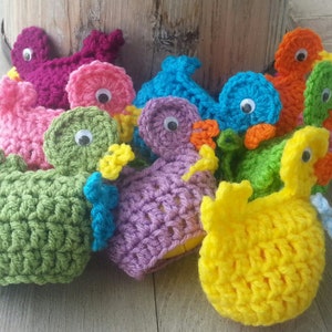 May include: A collection of crocheted Easter chick ornaments in various colors, including pink, green, purple, blue, yellow, and orange. Each chick has googly eyes and a beak.