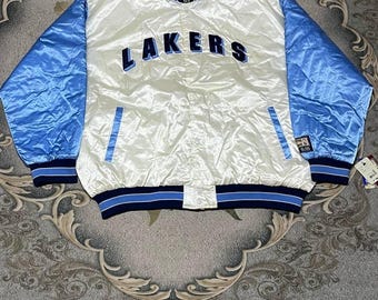 May include: A white satin baseball jacket with blue satin sleeves. The jacket has a blue and white striped collar and cuffs. The word "LAKERS" is embroidered in blue on the front of the jacket.