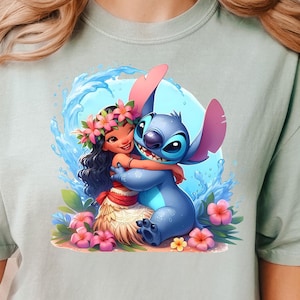 May include: A light blue t-shirt with a cartoon image of Stitch from Lilo & Stitch hugging a girl with brown hair and a flower lei. The girl is wearing a brown grass skirt and a pink flower behind her ear.