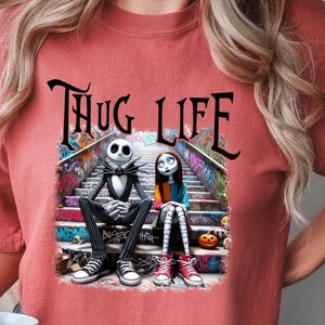 Puede incluir: Una camiseta roja con un gr&aacute;fico de Jack Skellington y Sally de Pesadilla antes de Navidad sentados en un tramo de escaleras con el texto "Thug Life" encima.