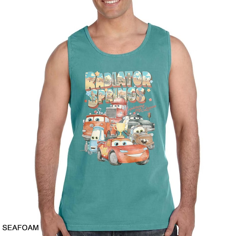 Puede incluir: Camiseta sin mangas verde mar con un gr&aacute;fico colorido de personajes de la pel&iacute;cula Cars, incluido Rayo McQueen. El texto "Radiator Springs" se muestra encima de los personajes en una fuente estilizada.
