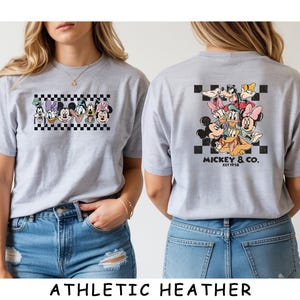 May include: A light gray t-shirt featuring a graphic of Disney characters on the front and back. The front shows a horizontal row of character faces over a black and white checkerboard. The back displays a larger group graphic with the text MICKEY & CO. EST 1928.