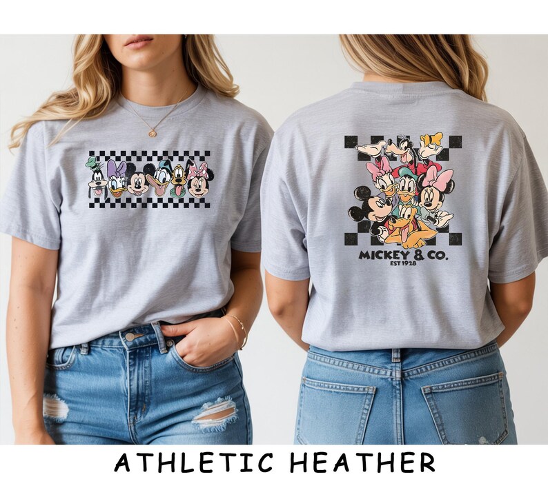May include: A light gray t-shirt featuring a graphic of Disney characters on the front and back. The front shows a horizontal row of character faces over a black and white checkerboard. The back displays a larger group graphic with the text MICKEY & CO. EST 1928.