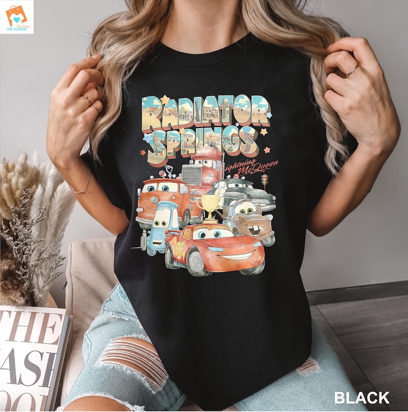 May include: Black t-shirt with a graphic print of the Cars characters from the movie Cars. The graphic features the text "Radiator Springs" and "Lightning McQueen".