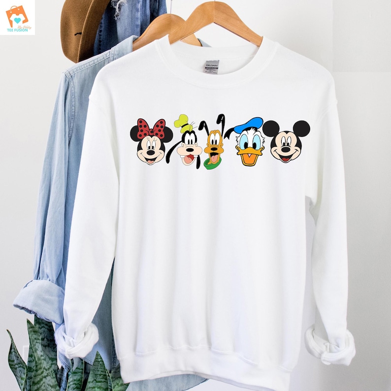 Op de afbeelding: Witte trui met een grafische print van Mickey Mouse, Minnie Mouse, Donald Duck, Goofy en Pluto. De personages lachen allemaal en hebben hun kenmerkende kenmerken.