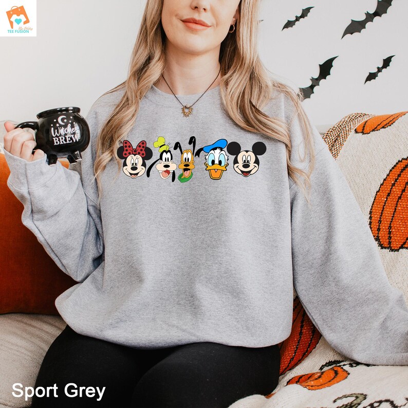Op de afbeelding: Een grijs sweatshirt met een print van Mickey Mouse, Minnie Mouse, Donald Duck, Goofy en Pluto. De personages zijn in een rij over de voorkant van het sweatshirt geplaatst.