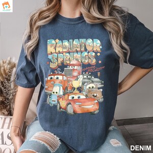 May include: A navy blue t-shirt with a graphic print of cartoon cars from the movie Cars. The graphic includes the text "Radiator Springs" and "Lightning McQueen".