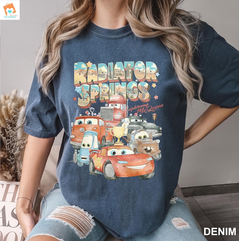May include: A navy blue t-shirt with a graphic print of cartoon cars from the movie Cars. The graphic includes the text "Radiator Springs" and "Lightning McQueen".