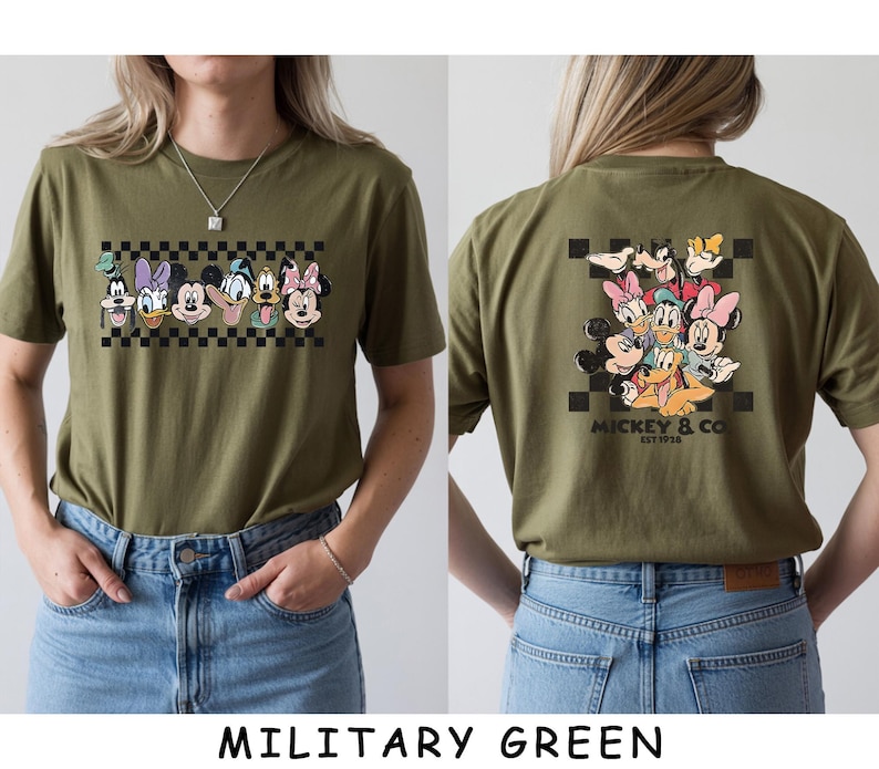 May include: An olive green t-shirt featuring a graphic of Disney characters including Mickey Mouse, Minnie Mouse, Donald Duck, Daisy Duck, Goofy, and Pluto. The front displays the characters in a row over a black and white checkerboard pattern.