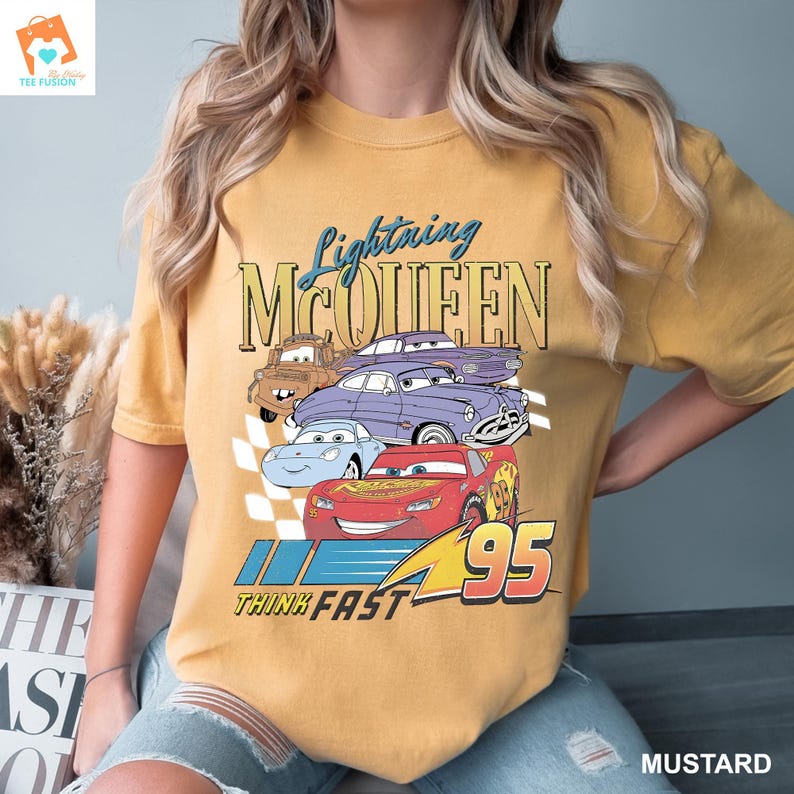 May include: A yellow t-shirt featuring a graphic of Lightning McQueen from the Cars film. The graphic includes the text "Lightning McQueen" and "Think Fast 95".