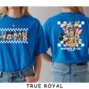 May include: A bright blue t-shirt featuring a graphic of Disney characters including Mickey Mouse, Minnie Mouse, Donald Duck, Daisy Duck, Goofy, and Pluto. The front shows their faces in a row, while the back displays them above the text Mickey & Co. Est 1928.