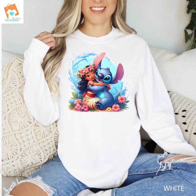 May include: A white long-sleeved shirt with a graphic of Stitch from Lilo & Stitch hugging a girl with a flower lei. The girl is wearing a blue dress and has brown hair. The graphic is set against a blue and white wave background.