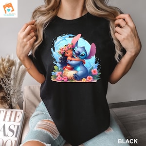 May include: Black t-shirt with a graphic of Stitch from Lilo & Stitch hugging Moana from Moana. The graphic is surrounded by blue water and pink flowers.