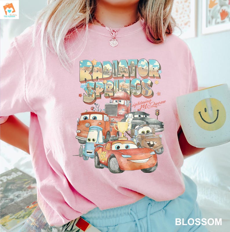 May include: Pink t-shirt with a graphic of the Cars characters from the movie Cars. The graphic includes the text "Radiator Springs" and "Lightning McQueen".
