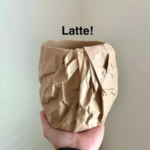May include: A beige ceramic planter with a crumpled paper texture. The planter is labeled "Latte!"