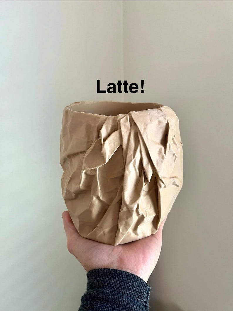 May include: A beige ceramic planter with a crumpled paper texture. The planter is labeled "Latte!"