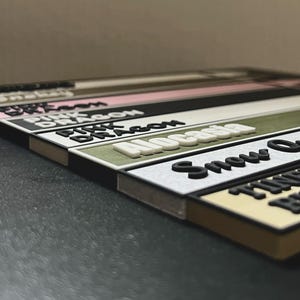 May include: A set of colorful, rectangular labels with different names printed on them, including "Pink Dragon", "Alcatraz", "Snow Queen", and "Timeless Beauty".