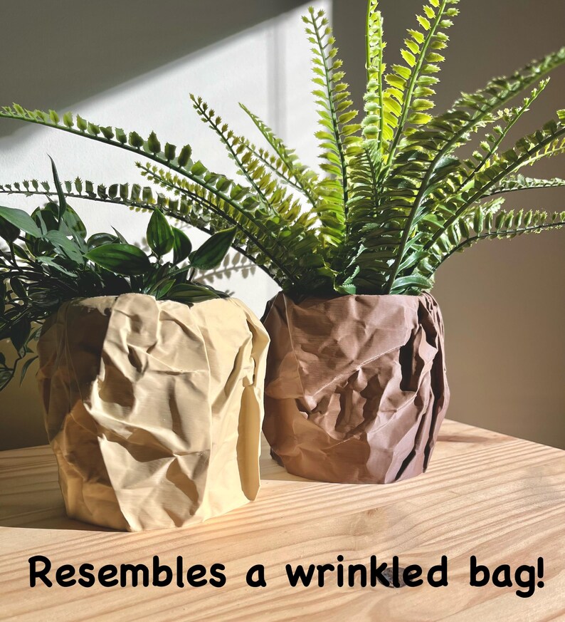 May include: Two potted plants with green leaves in brown and beige crumpled paper pots that resemble wrinkled bags.