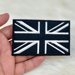 May include: Black iron-on patch with a white Union Jack flag design embroidered on it.