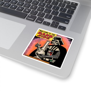 Puede incluir: Una pegatina cuadrada con una ilustración estilo cómic de Darth Vader sosteniendo un bong. El texto "WELCOME TO THE DANK SIDE" está en una pancarta amarilla. El fondo es naranja y rojo.