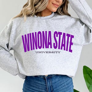 Puede incluir: Una sudadera gris con el texto "Winona State University" en morado.
