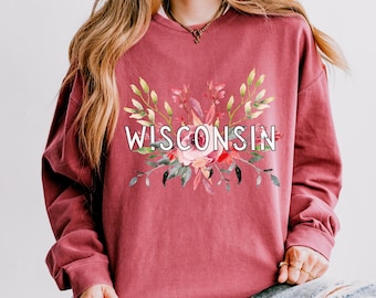 May include: A maroon long-sleeved sweatshirt with a floral design and the text "WISCONSIN" in white.