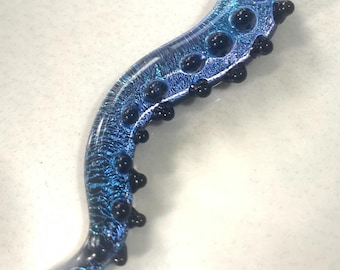 May include: A blue glass pendant necklace with a textured surface and black glass accents. The pendant is shaped like an octopus tentacle.