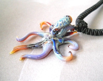 May include: A glass octopus pendant with a black cord necklace. The octopus is made of iridescent glass with blue, purple, and orange colors.