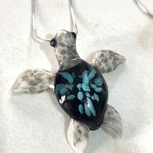 Les pendentifs bébé tortue grise ont été nommés bébé gris du nom d&#39;une véritable histoire de tortue de mer ci-dessous